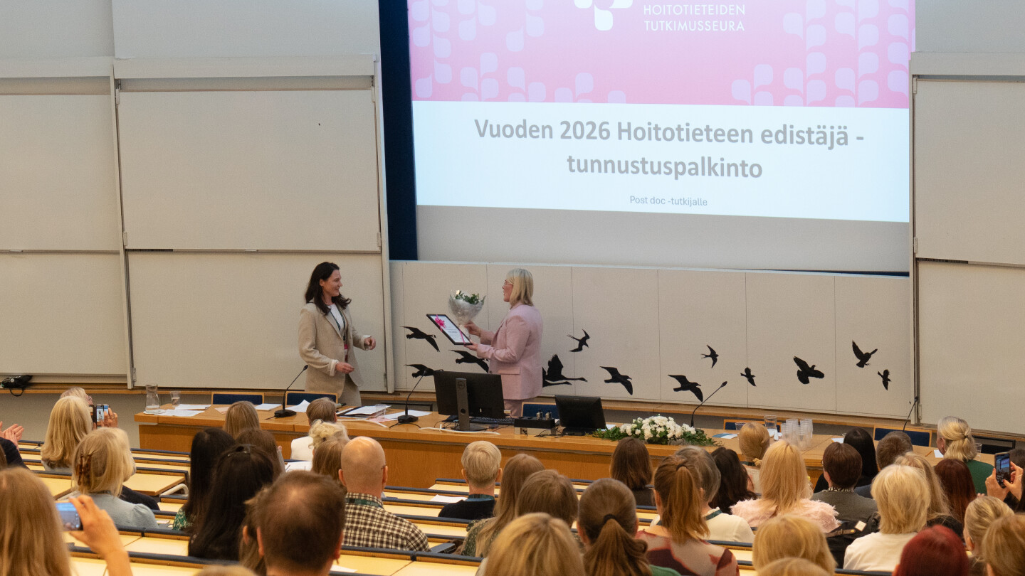 Palkittu ottamassa palkinnon vastaan luentosalissa