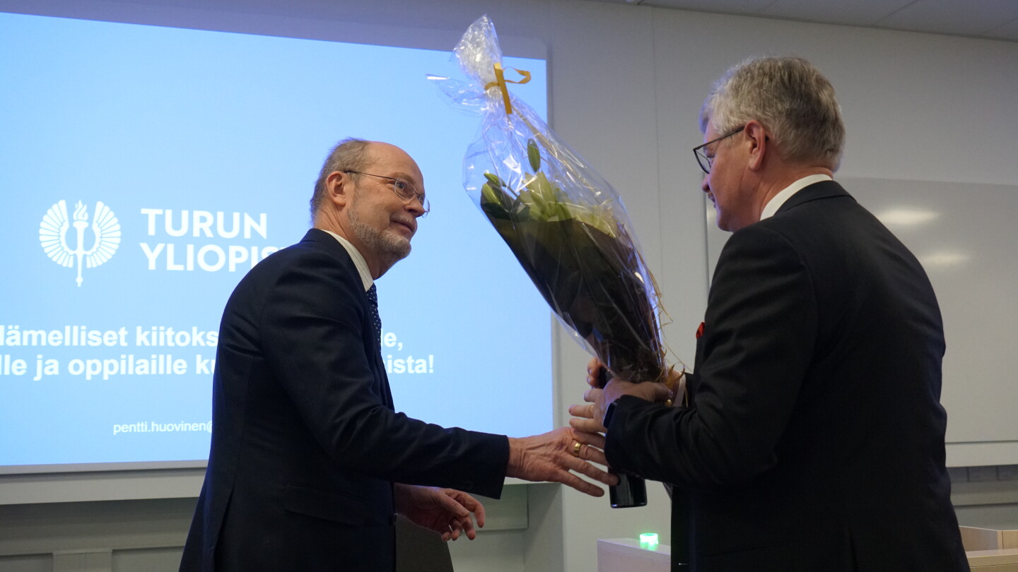 Dekaani Hänninen ojentamassa kukkia Pentti Huoviselle