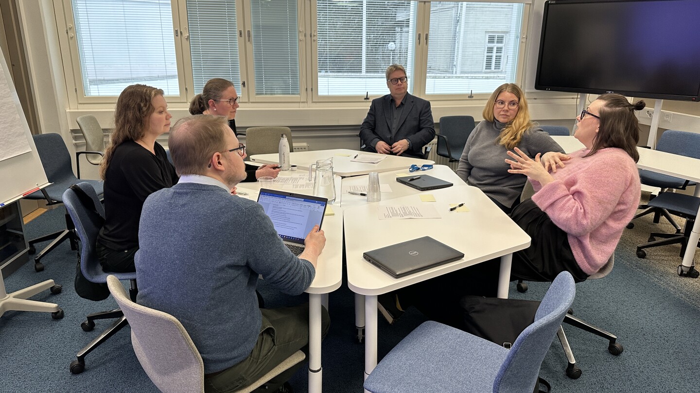 Six people sitting around a table discussing