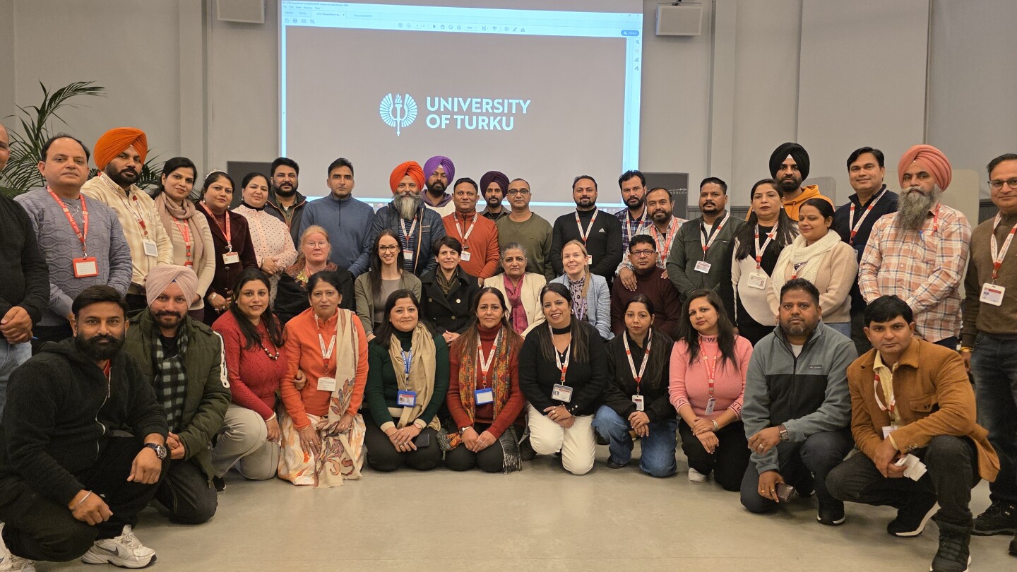 A large group of people standing in front a screen looking at the camera