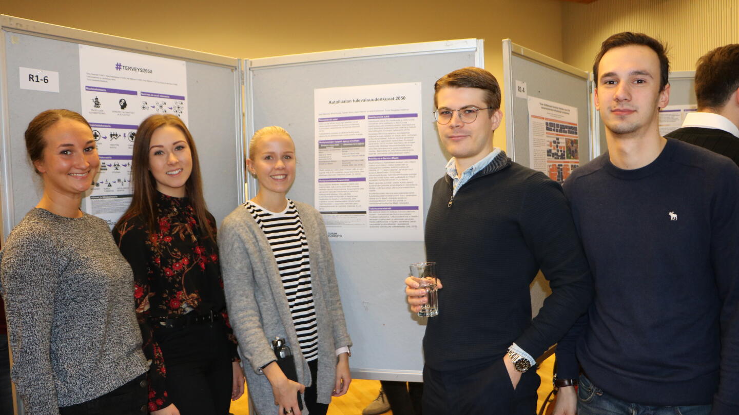 Opiskelijat Autoilualan tulevaisuudenkuvat 2050 -posterin ympärillä