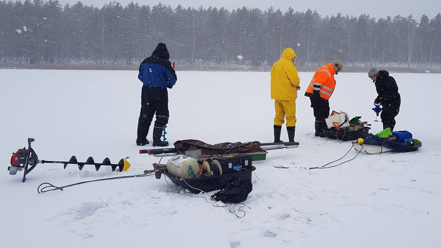 Tutkija ryhmä latvialaisjärven jäällä ottamassa näytteen järven pohjakerroksista
