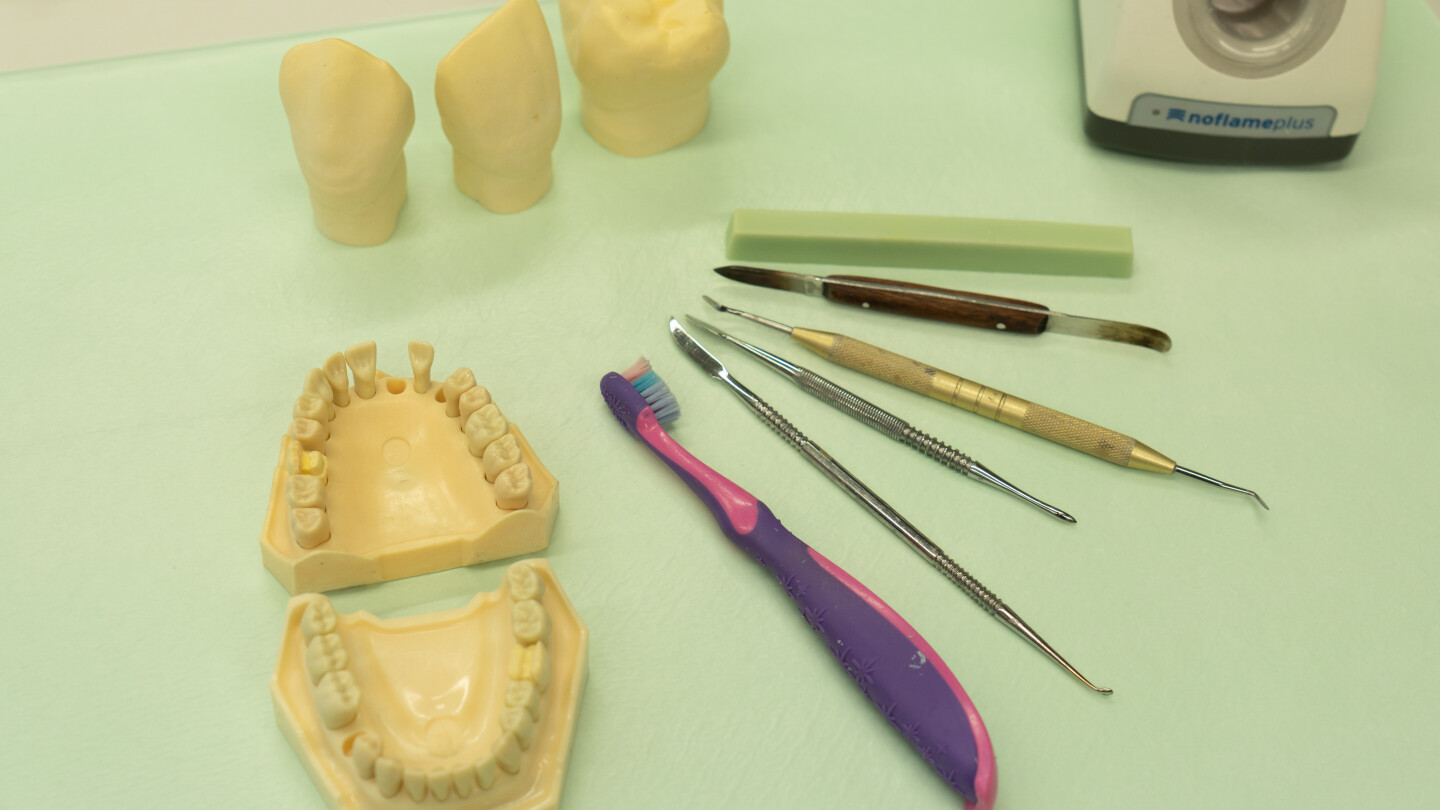 Pöydällä hammaslääkärin työkaluja ja muovisia hampaita