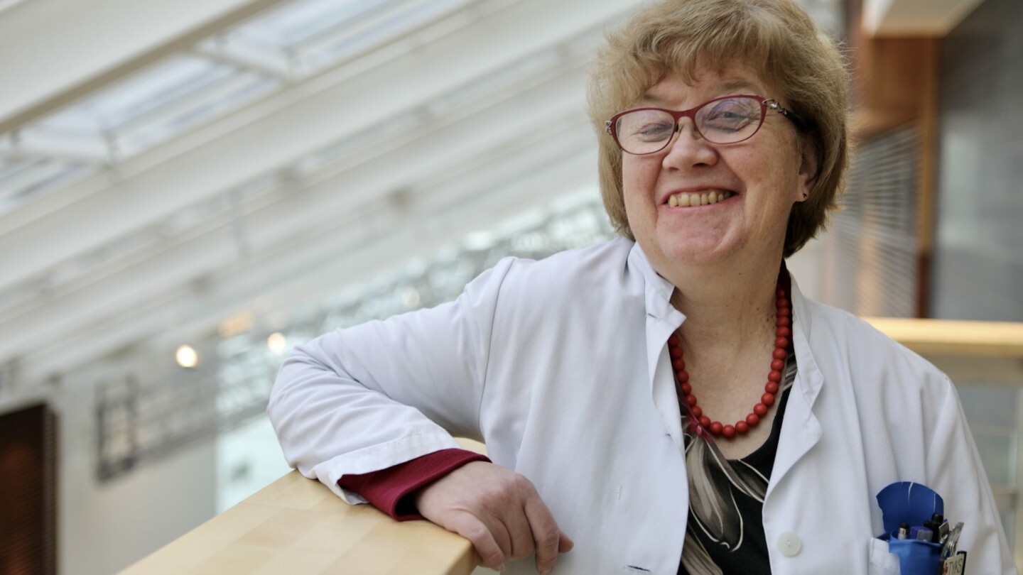 Professor Tarja Saaresranta is leaning on a railing in a white doctors coat.