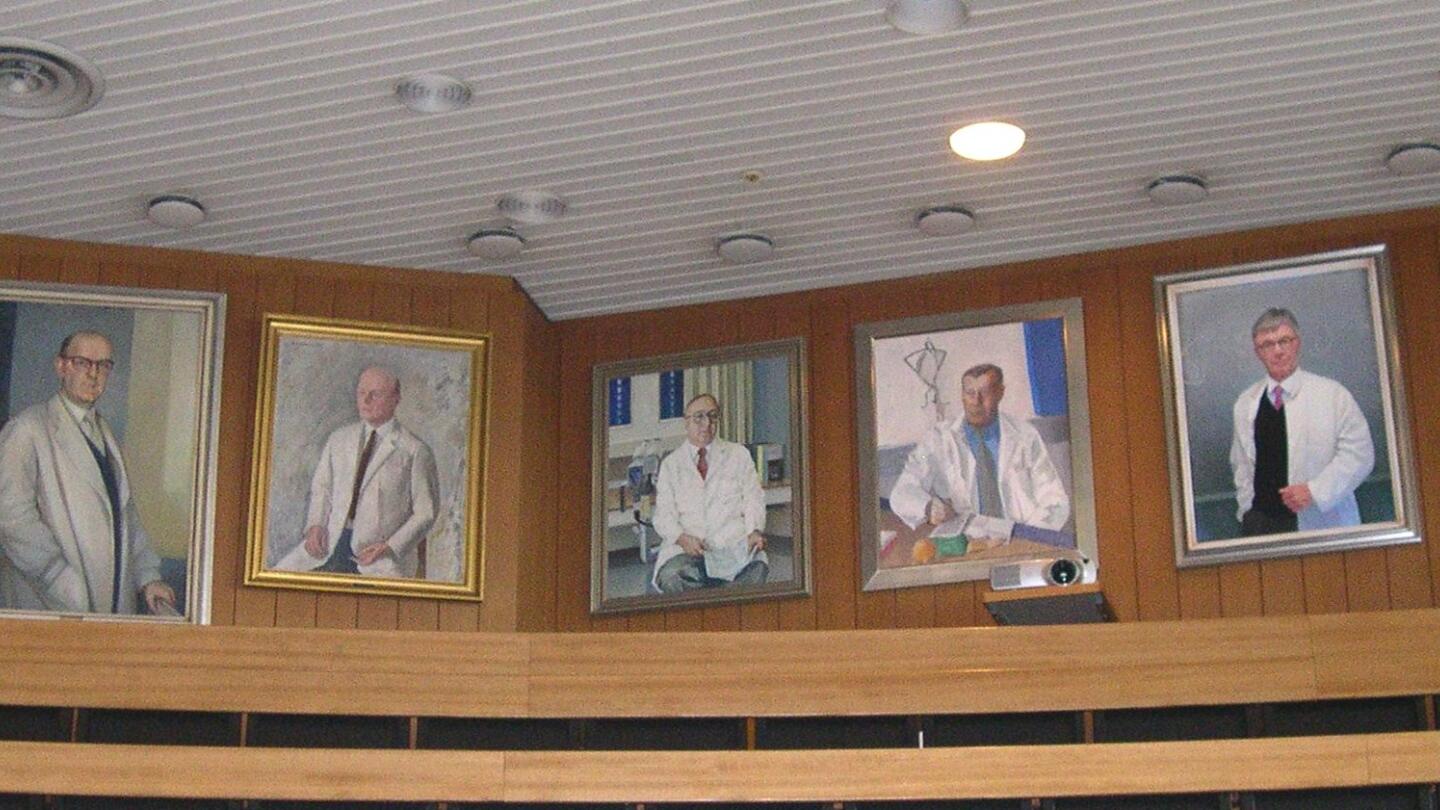 Naistenklinikan professorien muotokuvat luentosalin seinällä