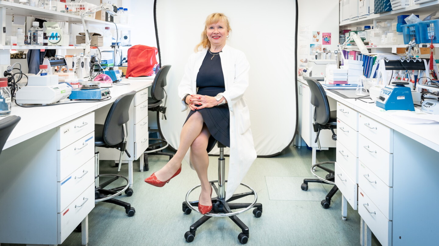 Sirpa Jalkanen is sitting in laboratory in front of a white screen.