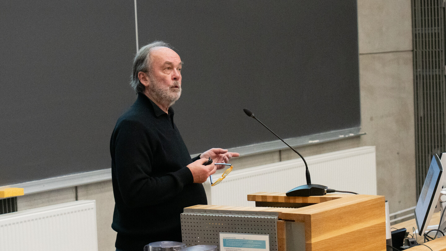 Hasse Karllson puhumassa luentosalin edessä