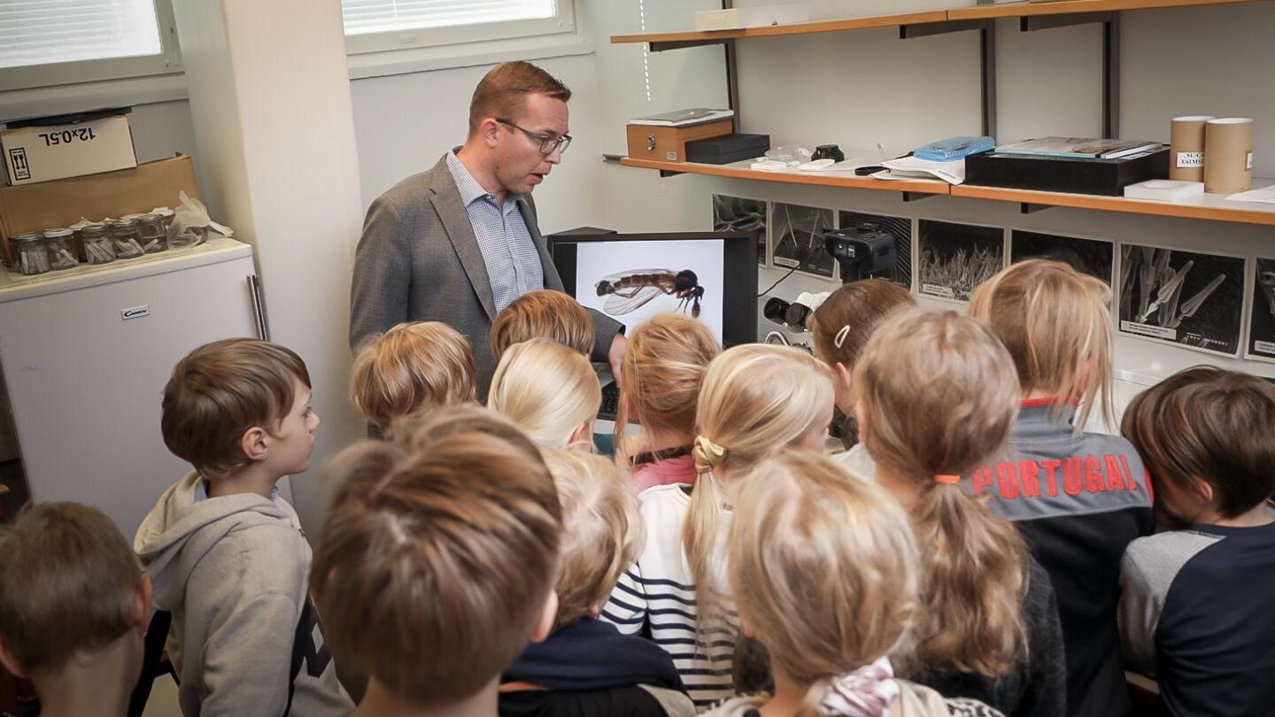 Ilari Sääksjärvi esittelee koululaisille mikroskooppeja.