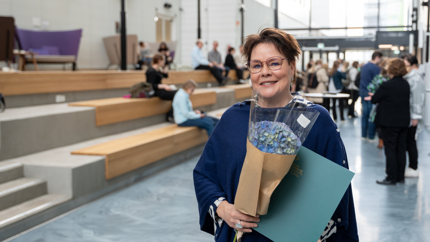 Benita Heiskanen lähikuvassa, pitää käsissään kukkakimppua ja diplomia.