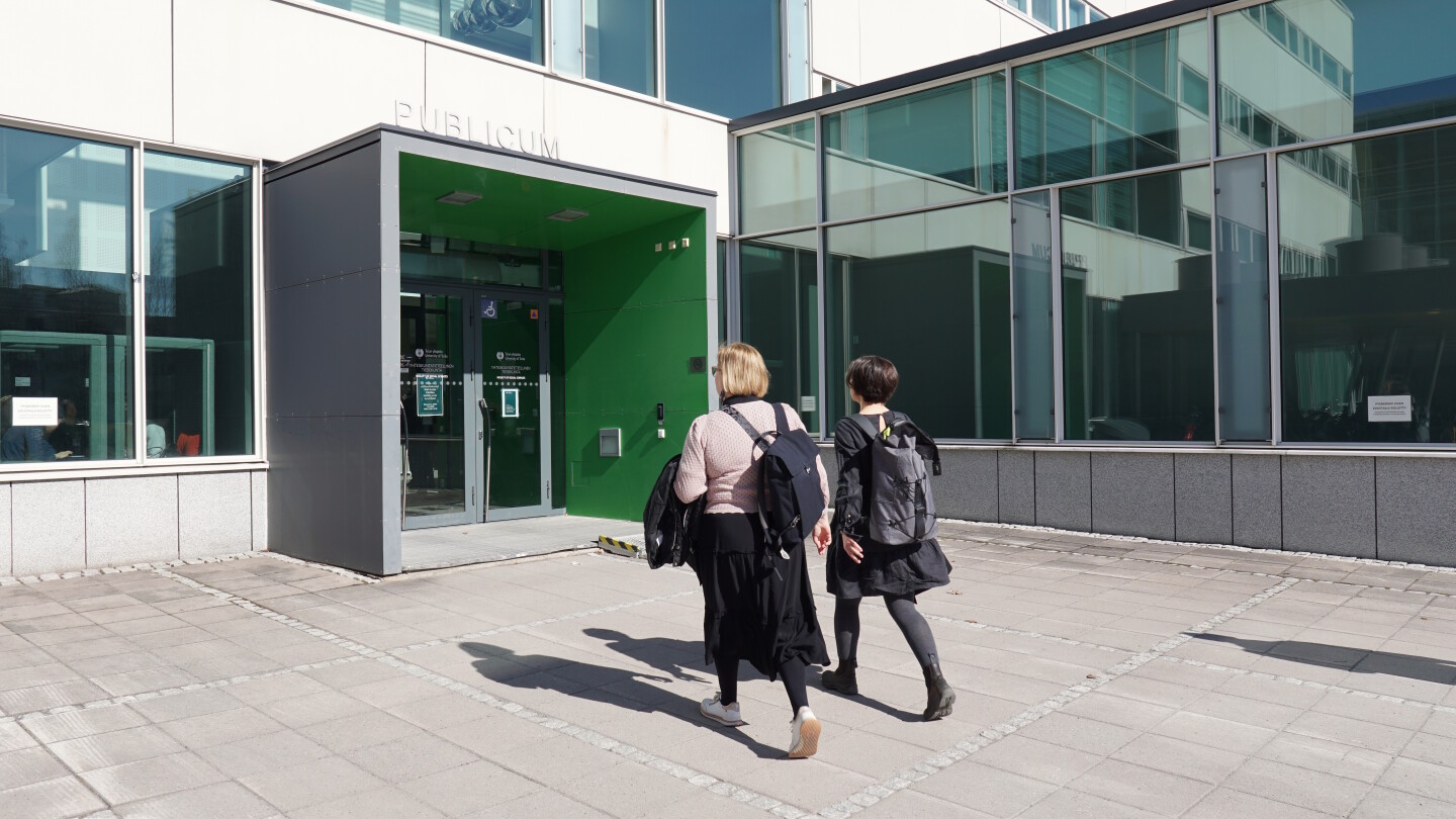 Kaksi naista kävelemässä sisälle rakennukseen.