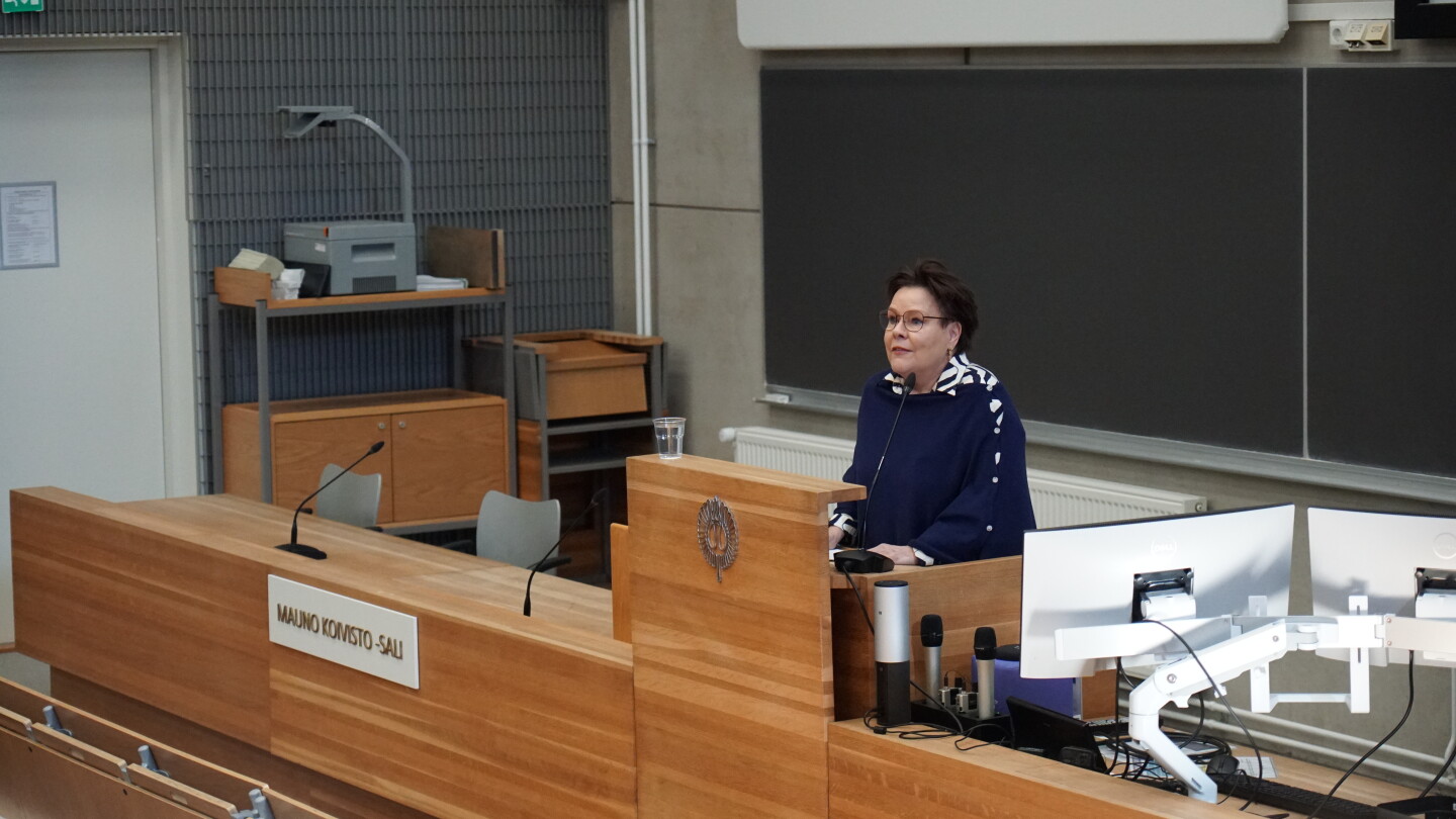 Nainen puhumassa luentosalissa.