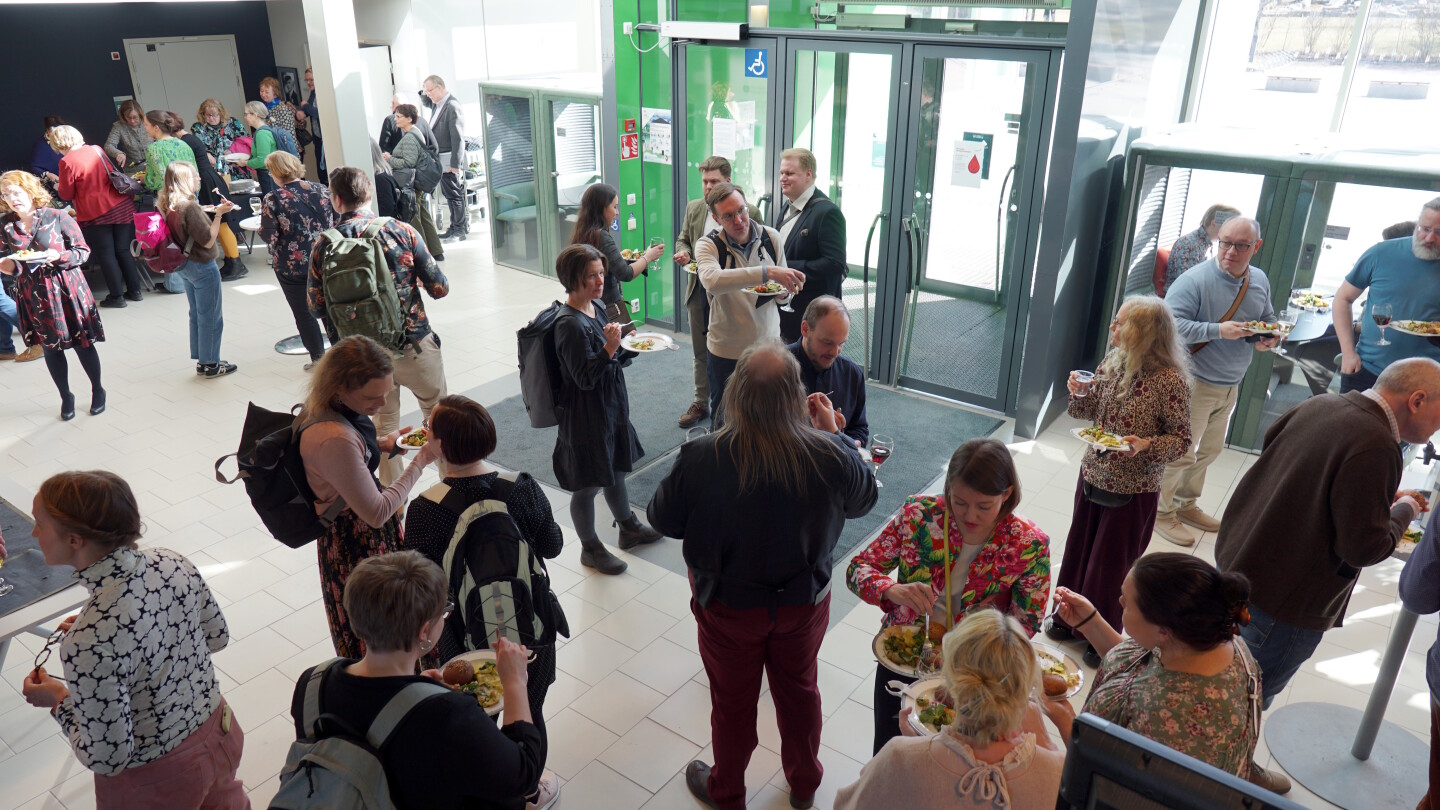 Ihmisiä seurustelemassa rakennuksen aulassa.