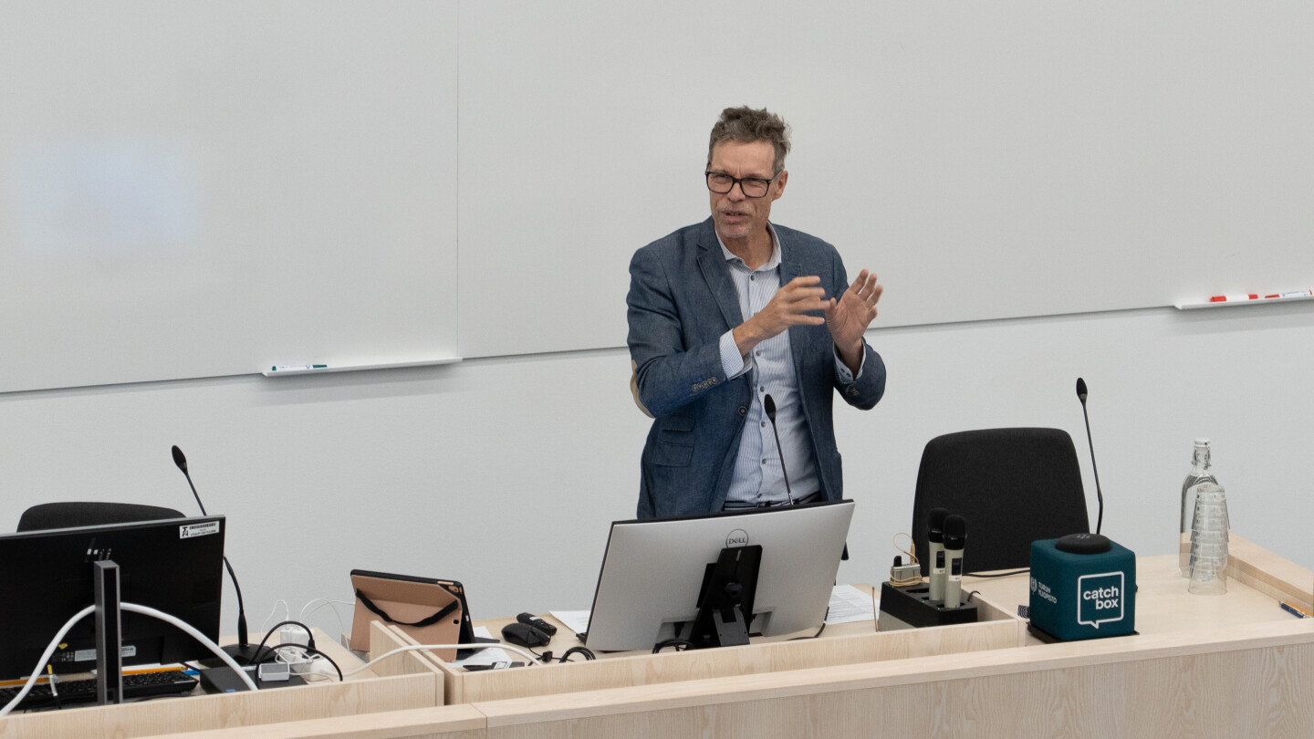Tarmo Martikainen puhuu luentosalin edessä