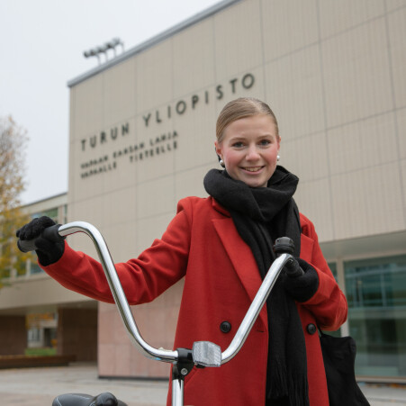 Nainen pyörän kanssa Turun yliopiston päärakennuksen edessä