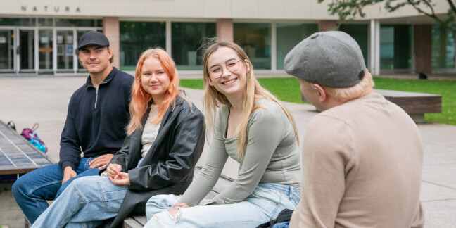 Neljä henkilöä istumassa ulkona ja juttelemassa.