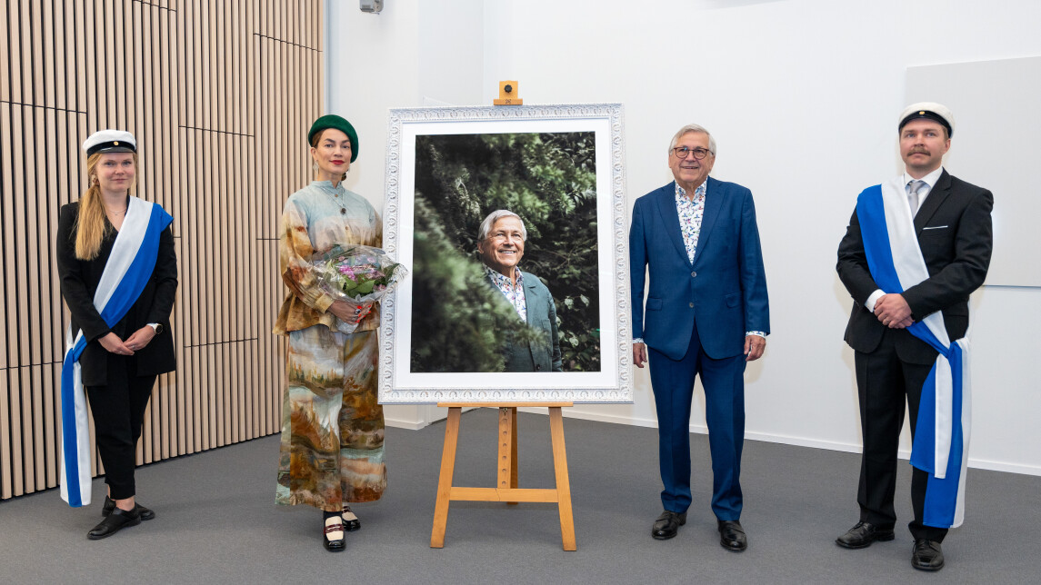 Ihmiset poseeraamassa muotokuvan ympärillä