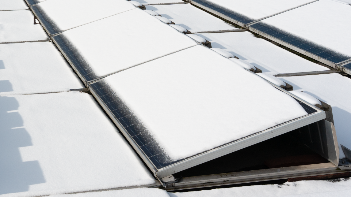 kuva lumen peittämistä aurinkopaneeliriveistä rakennuksen katolla