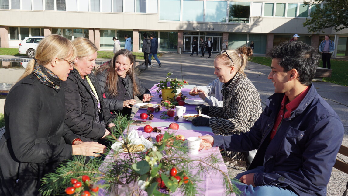 Ihmiset istumassa koristellun pöydän äärellä ulkona Yliopistonmäellä.