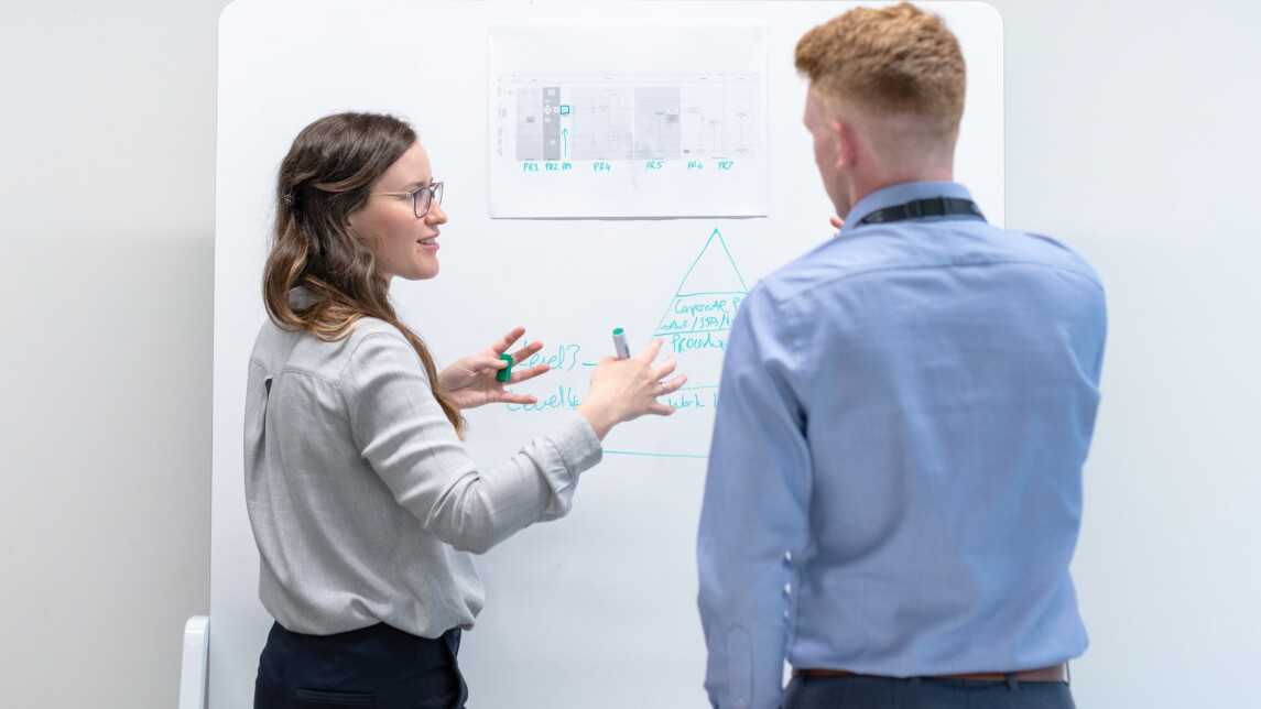 Kaksi ihmistä esittämässä taululta