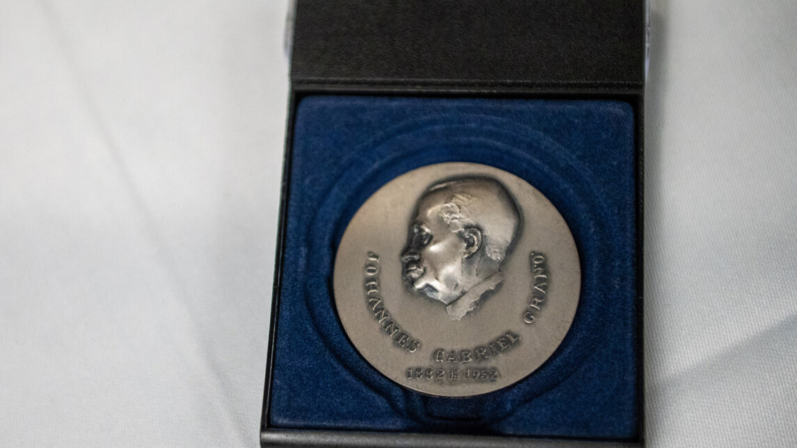 J.G. Granö -mitali sinisen sametin päällä mitalikotelossa. Mitalikotelo on pöydällä valkean pöytäliinan päällä