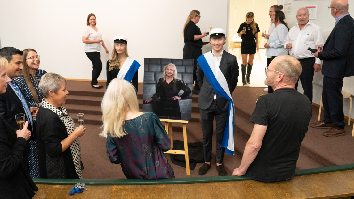 Ihmisiä juhlatilaisuudessa katsomassa muotokuvaa