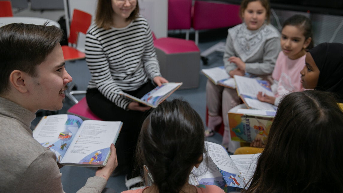 Alakouluikäisiä lukemassa aikuisten kanssa.