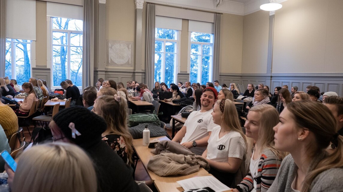 Opiskelijoita istumassa salissa