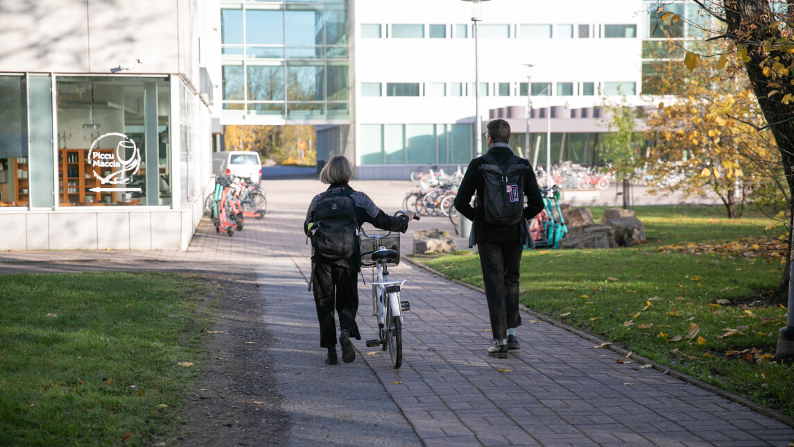 Kaksi opiskelijaa kävelemässä yliopiston kampuksella.