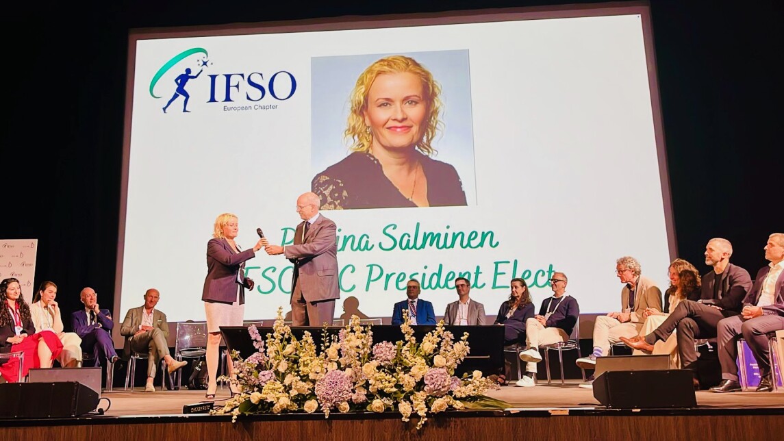 Paulina Salminen kävelemässä lavalle. Tausta IFSO-logo ja Salmisen kuva valkokankaalla