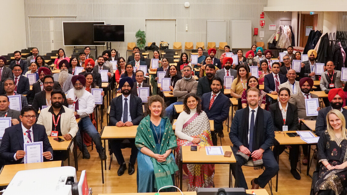 A group of people sitting in a lecture hall holding their certificates.