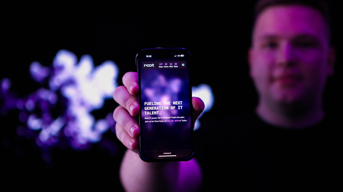 Henkilö pitelee älypuhelinta, jonka näytölle on kirjoitettu tekstiä. Taustalla on violettia valoa.