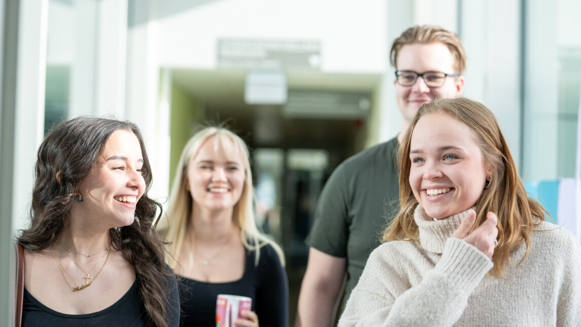 Neljä hymyilevää opiskelijaa Publicumin käytävällä