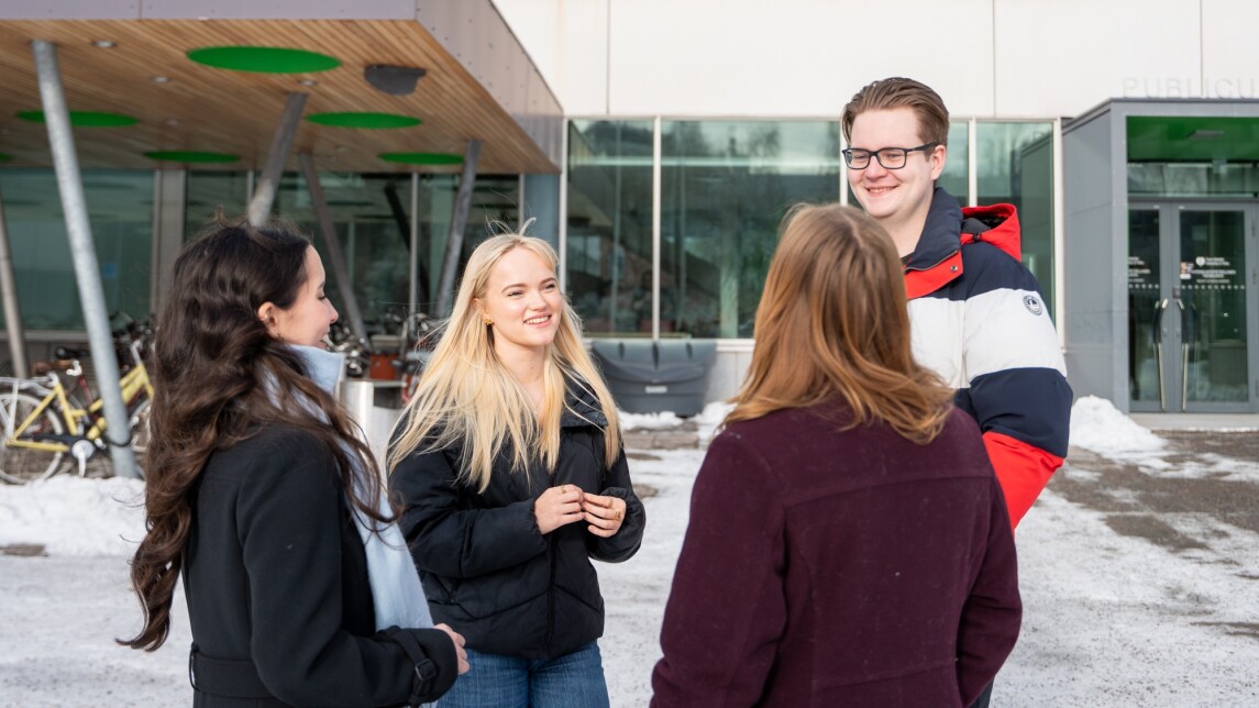 Neljä opiskelijaa keskustelee Turun yliopiston Publicum-rakennuksen edessä