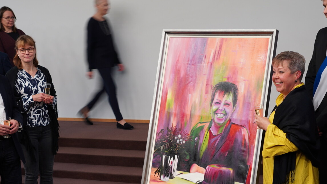 Satu Lahti kollegoineen muotokuvan ympärille kokoontuneena.