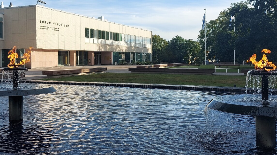 Yliopistonmäen aukio, jossa suihkulähteessä palavat soihdut ja päärakennus taustalla.