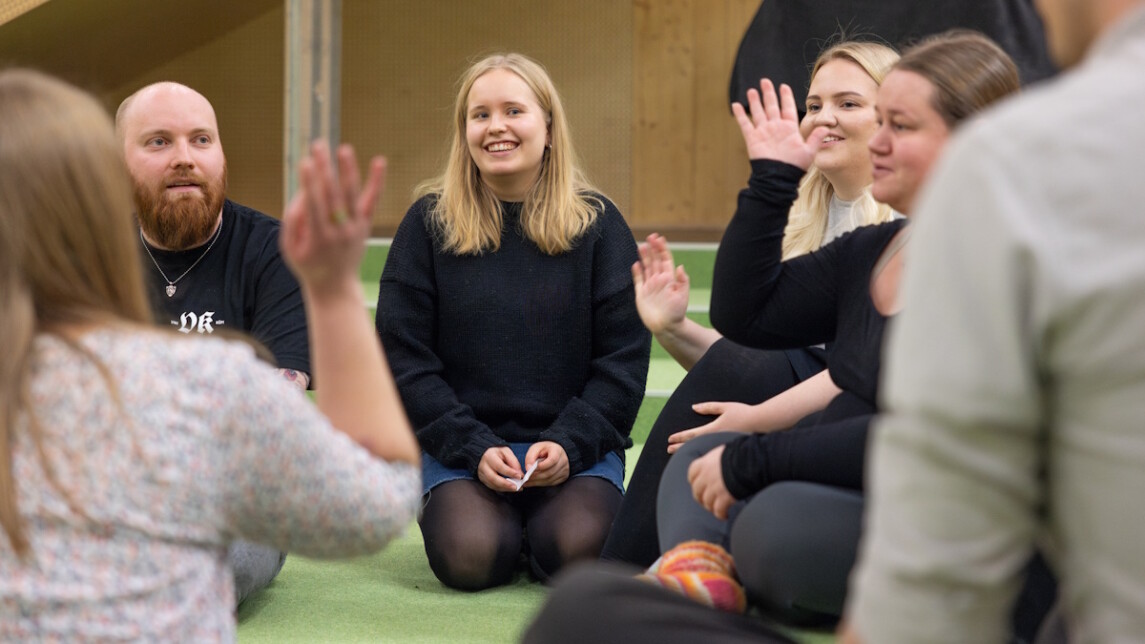 Ihmisiä istumassa lattialla keskustelemassa.