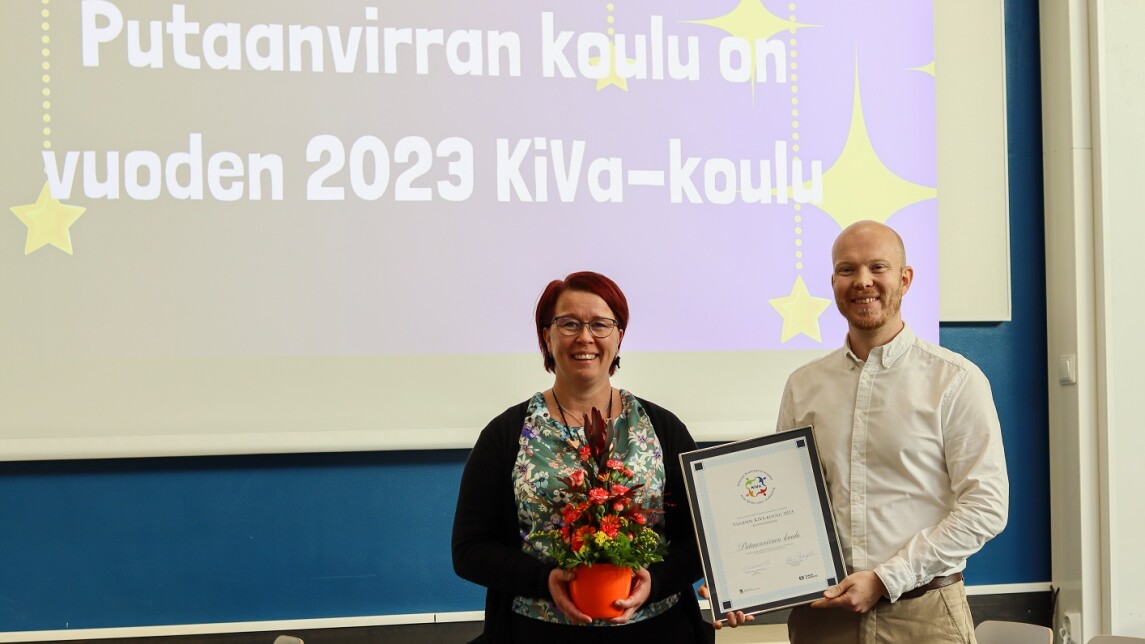 Kaksi henkilöä kunniakirjan kanssa.