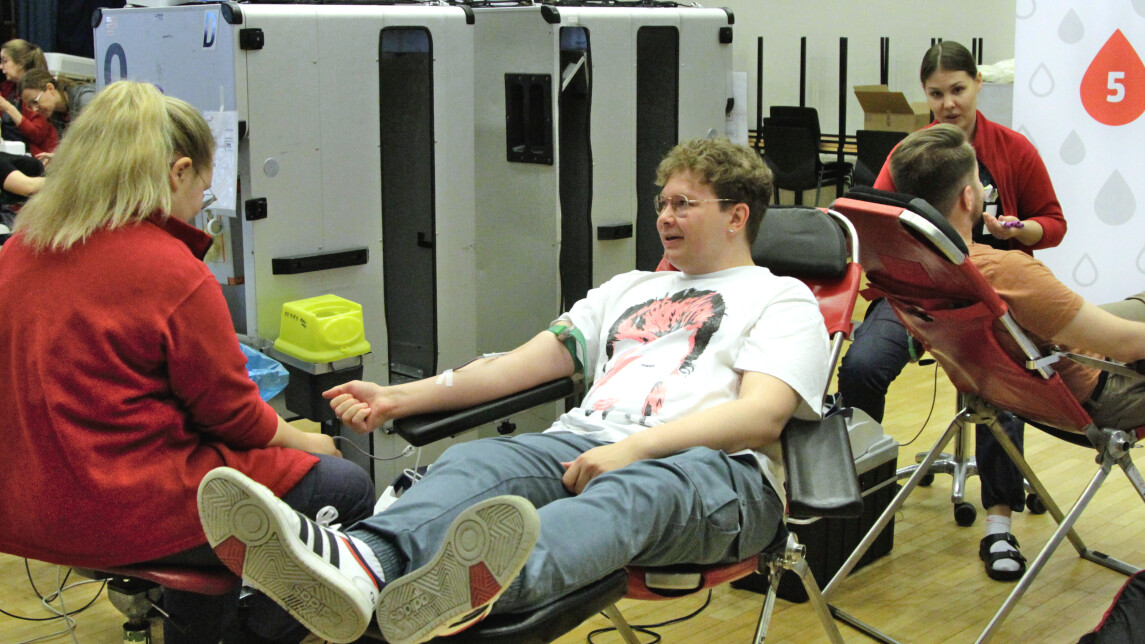 Opiskelija istuu hoitajaa vastapäätä verenluovutuspenkissä