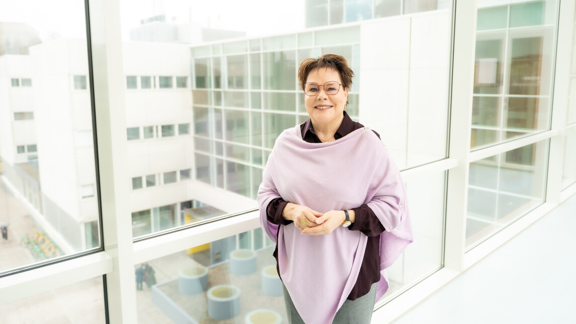 Benita Heiskanen lähikuvassa, taustalla olevasta ikkunasta näkyy Turun alakampusta.