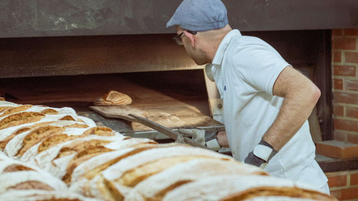 Leipuri asettelemassa leipää leipäuuniin