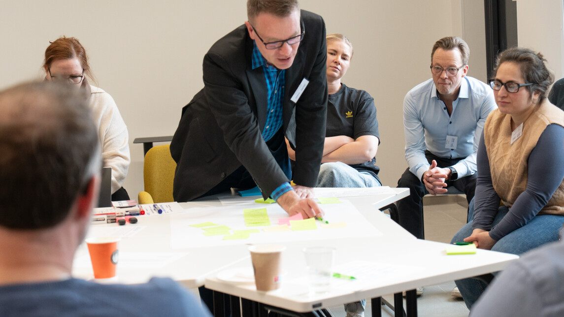 Ihmisiä kirjoittamassa yhdessä tussilla isolle paperille