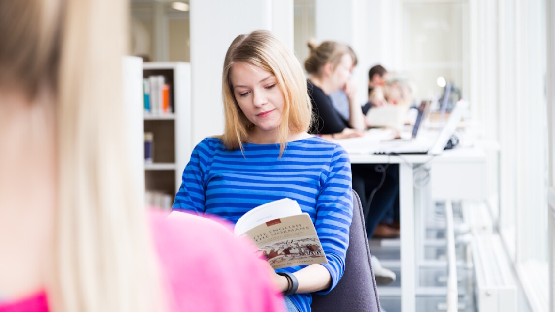 Opiskelijat lukevat kirjoja yliopiston kirjastossa.