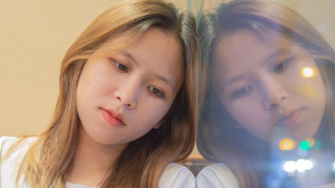 Alakuloisen oloinen nuori nojaa heijastuvaan ikkunaan.