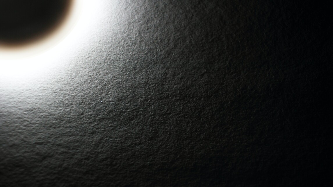 Auringonpimennystä muistuttava lampun kajo paperia vasten