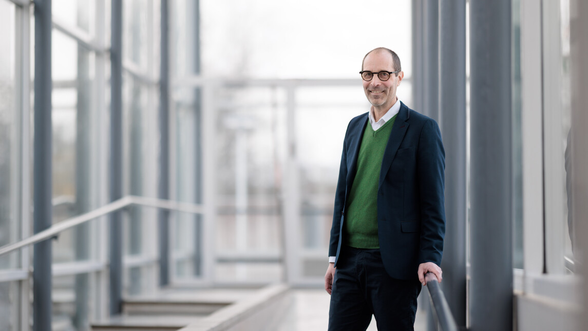 Dekaani Jaakko Järvi henkilökuvassa valoisalla lasiseinäisellä käytävällä kampuksella