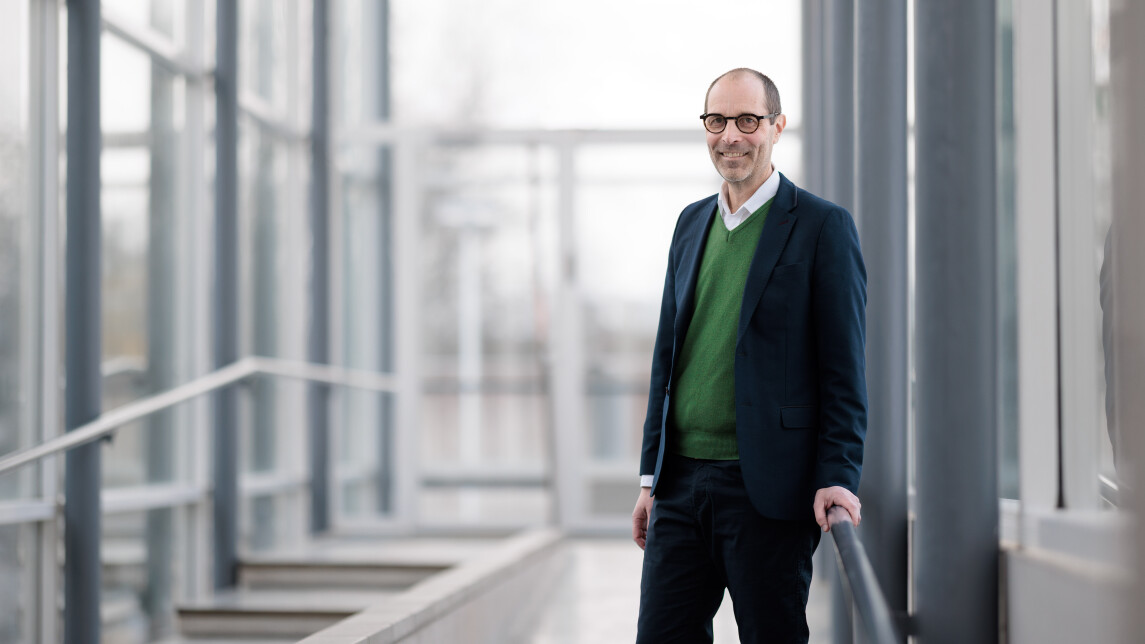 Dekaani Jaakko Järvi henkilökuvassa valoisalla lasiseinäisellä käytävällä kampuksella