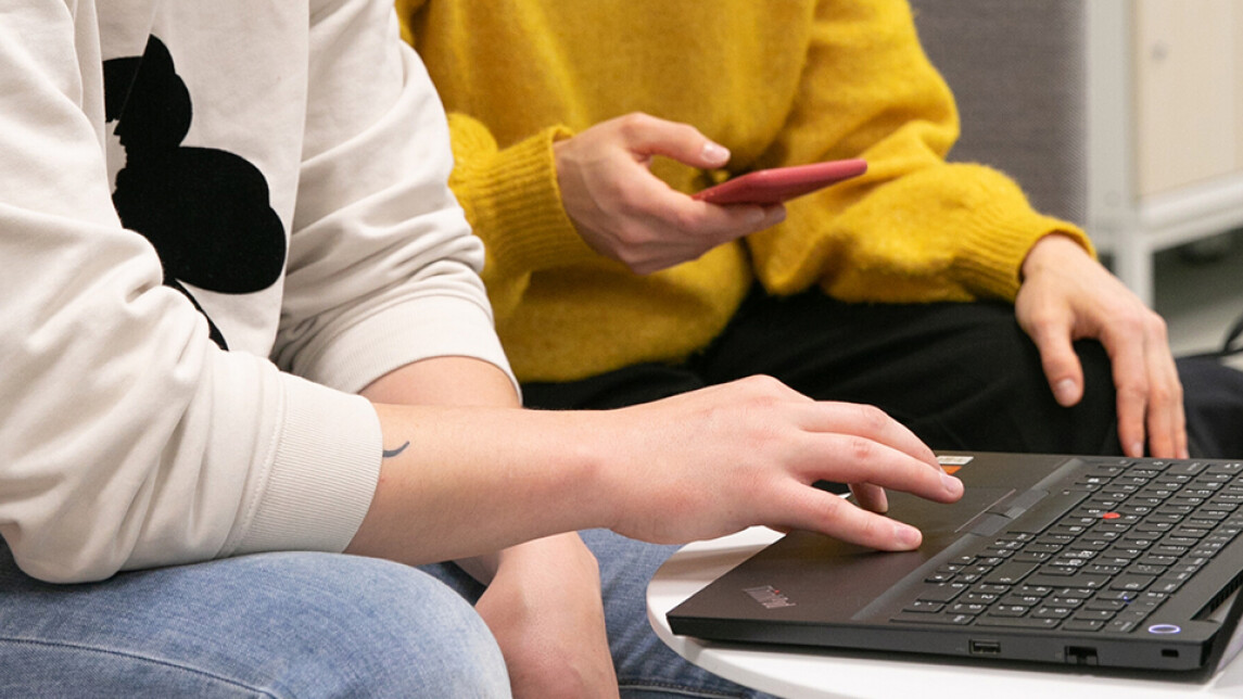 Kaksi henkilöä katselee läppäriä, vain heidän kätensä näkyvät.