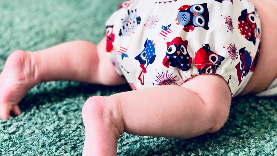 Kuvituskuva vauvasta, jolla iloisen värinen vaippa. 