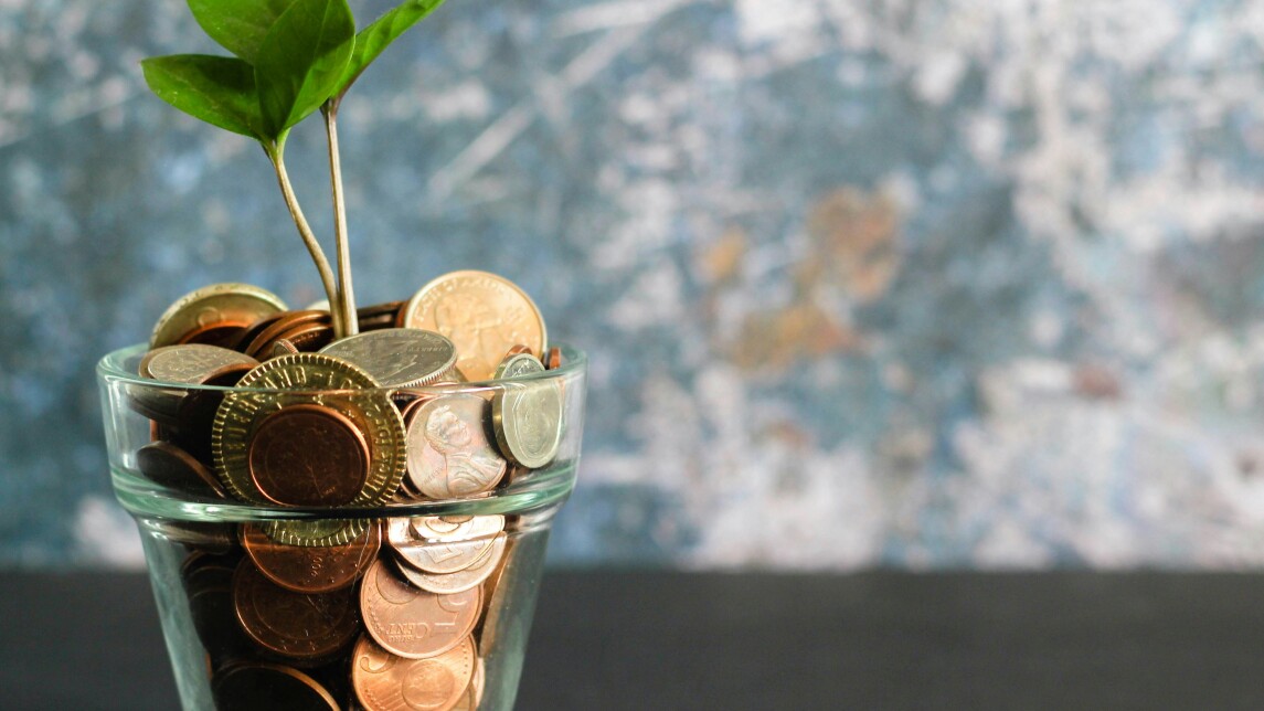Plant growing out of glass full of coins