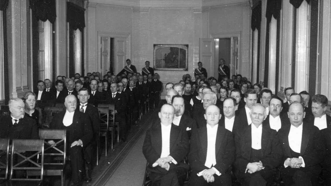 Turun yliopiston ensimmäisen päärakennuksen Phoenixin juhlasalissa suuri joukko juhlapukuihin pukeutuneita henkilöitä.